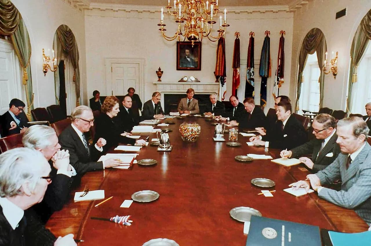 Ronald Reagan's Cabinet and Margaret Thatcher's Ministry meet in the White House Cabinet Room. A large jar of jelly beans sits prominently on the cabinet room t